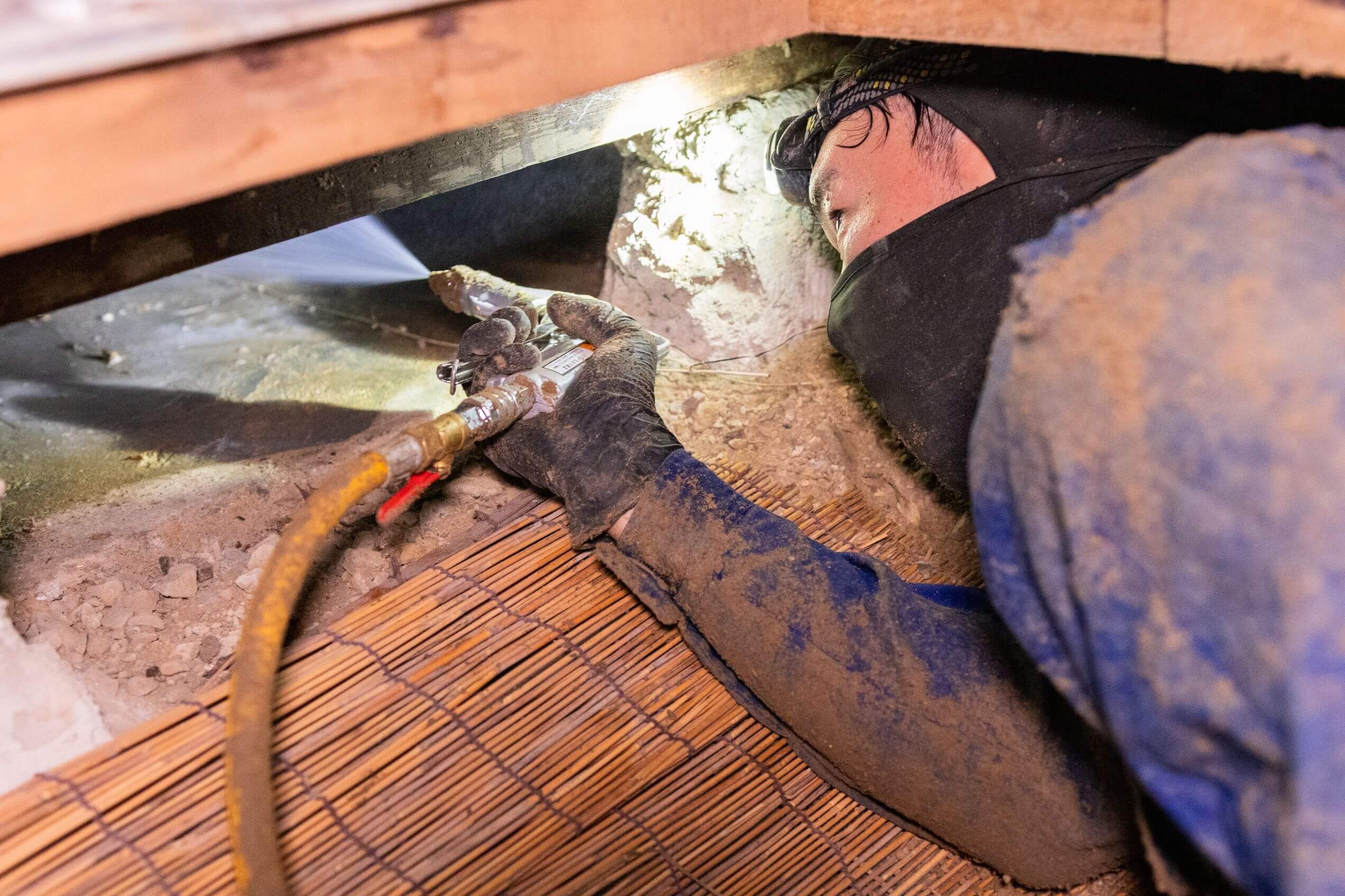 堺市の戸建て住宅の床下でシロアリ薬剤を散布する様子